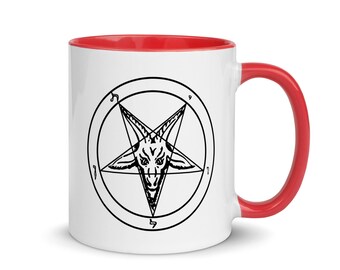 May include: White ceramic coffee mug with a red rim and handle. The mug features a black and white illustration of a pentagram with a goat's head inside.