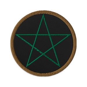 Puede incluir: Un parche circular negro con un borde marrón, en el que se borda un pentagrama verde.