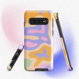 May include: A set of three phone cases with a colorful abstract design. The cases feature a pattern of organic shapes in shades of yellow, purple, pink, and green. One case is upright, another is leaning, and the third is lying down.