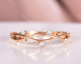 May include: A delicate rose gold band ring with a vine design and three small white opal stones.