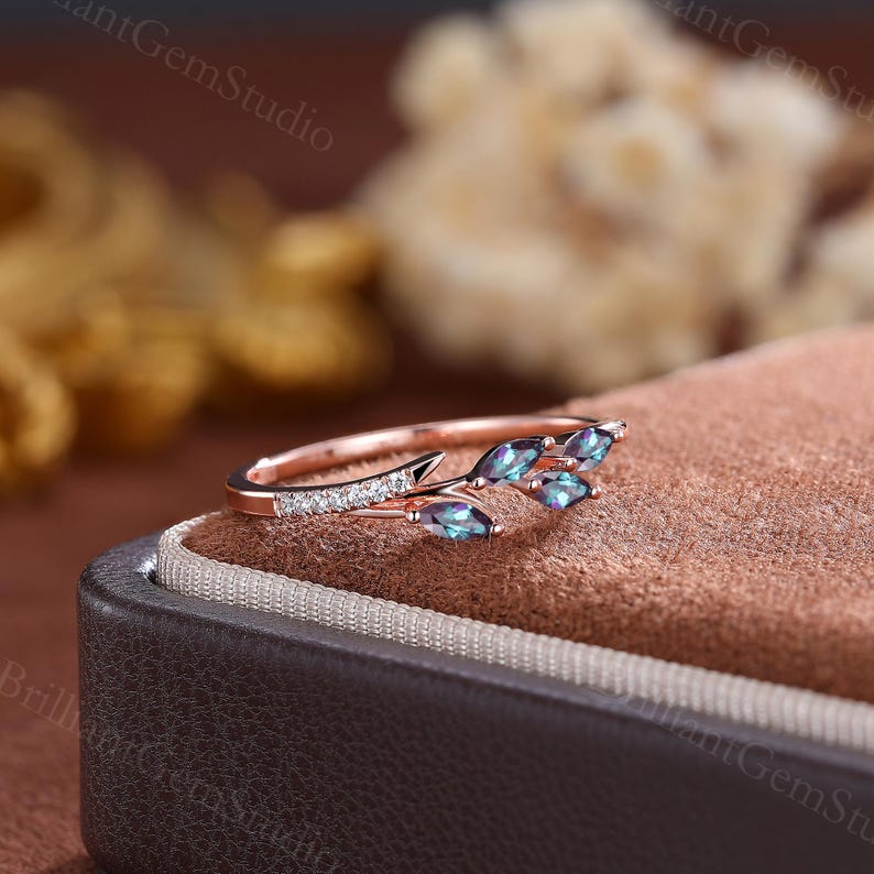 May include: A rose gold ring with a delicate branch design featuring five marquise-shaped alexandrite gemstones. The ring is set with small round diamonds along the band.