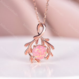 May include: A delicate rose gold necklace with a pink opal gemstone set in a branch-like pendant.