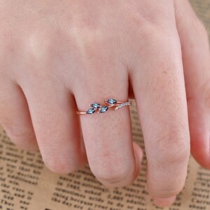 May include: A rose gold ring with a delicate branch design featuring blue gemstones and small white diamonds.