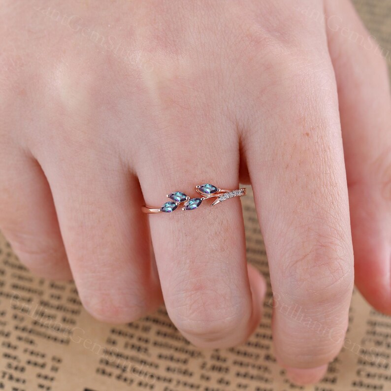 May include: A rose gold ring with a delicate branch design featuring blue gemstones and small white diamonds.