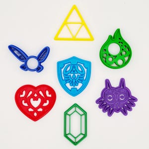 May include: A selection of brightly coloured, stylised shapes, including a yellow triangle, a blue shield, a green flame, a red heart, a green gem, a blue fairy, and a purple mask. These shapes are likely themed after a popular video game.