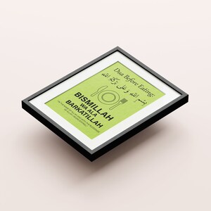 May include: Framed print with a black border. The print has a light green background with text in English and Arabic. The text includes "Dua Before Eating" and "BISMILLAH WA ALA BARKATILLAH". A fork, knife, and plate graphic are also present.