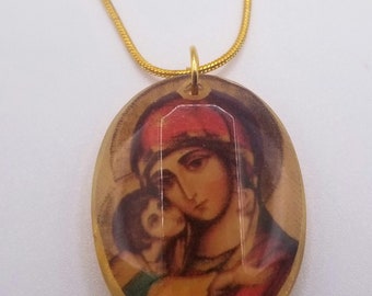 May include: Gold-toned necklace featuring an oval pendant with a religious image. The pendant depicts a woman and child in warm tones of red, brown, and gold. The chain is a delicate, thin design.