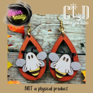 May include: A pair of laser cut wooden earrings shaped like teardrops with a ghost bee design. The earrings are painted orange and white with black accents. The text "Laser Ready" is visible in the image.