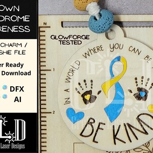 May include: A wooden car charm or keychain with a blue and yellow ribbon, two handprints, and the text "In a world where you can be anything, be kind".