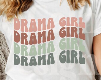 Könnte beinhalten: Weißes T-Shirt mit dem Text "Drama Girl", der viermal in einer Retro-Schrift wiederholt wird. Jedes Wort hat eine andere Farbe: rosa, braun, grün und grau.