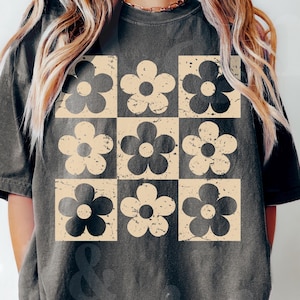 Peut inclure: Un t-shirt gris foncé avec un motif vintage de fleurs beiges et noires répétées.