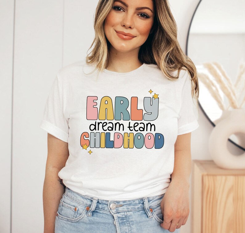 May include: White t-shirt with a colorful graphic that says "Early dream team childhood" with stars.