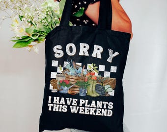 May include: Black tote bag with white text that reads "Sorry I have plants this weekend". The bag features a checkered pattern and a graphic of gardening tools and plants.