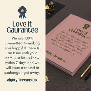 May include: A pink book with the text "Love It Guarantee" and a guarantee statement. The book is on a dark surface with office supplies. The text on the book states that the company is committed to making customers happy.