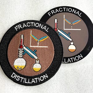Könnte beinhalten: Zwei runde Aufnäher mit braunem Hintergrund, schwarzem Rand und weißem Text FRACTIONAL DISTILLATION. Das Design zeigt eine gestickte Labordestillationsapparatur mit Thermometer, Kolben und einem Diagramm.