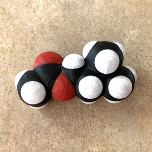 May include: A 3D model of a molecule with black, white, and red spheres connected by black rods.