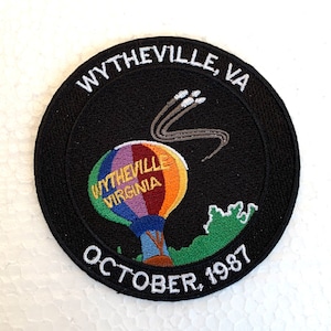 Pode incluir: Um remendo bordado preto e branco com um balão de ar quente e o texto "Wytheville, Virgínia, outubro de 1987".