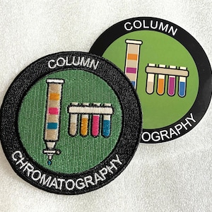 May include: A circular embroidered patch and a matching circular sticker featuring a green background, a chromatography column, and a test tube rack. Both items display the text COLUMN CHROMATOGRAPHY in white lettering along the black border.