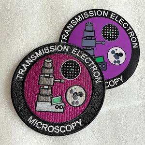 May include: Two circular patches featuring a transmission electron microscope graphic. One patch has a magenta background, the other purple. Both display the text TRANSMISSION ELECTRON MICROSCOPY in white lettering along the black border.