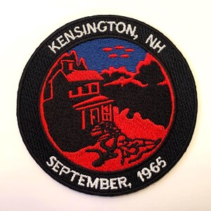 May include: A black and red embroidered patch with the text "KENSINGTON, NH SEPTEMBER, 1965" and a silhouette of a house with a blue sky in the background.