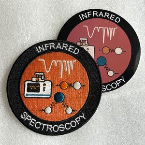 May include: A circular embroidered patch with an orange background and a black border featuring the text INFRARED SPECTROSCOPY, a white spectral graph, a white instrument icon, and molecular diagrams with orange, blue, and white spheres.