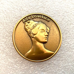 以下が含まれることがあります： エッジに「Ada Lovelace」という文字が刻まれた、Ada Lovelaceの肖像画が描かれた金色のコインです。