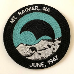 May include: A black and white embroidered patch with a mountain scene and the text "MT. RAINIER, WA JUNE, 1947".