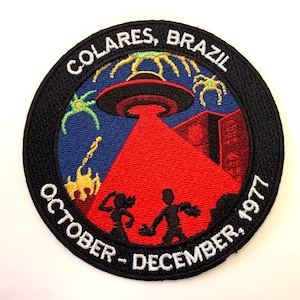 Puede incluir: Un parche bordado en blanco y negro con un OVNI, dos figuras y el texto "COLARES, BRASIL OCTUBRE - DICIEMBRE 1977".