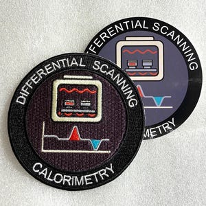 Peut inclure: Un écusson brodé circulaire et un autocollant circulaire assorti portant le texte "DIFFERENTIAL SCANNING CALORIMETRY". Les deux articles présentent un graphique d'instrument de laboratoire avec une courbe de données rouge et bleue.