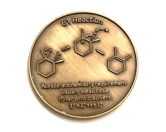 May include: A gold-colored coin with the text "E1 Reaction" and a chemical diagram. The coin also includes the text "No stereochemistry requirement", "Usually weak base", "Polar protic solvent", and "3°>2°>>>1°".