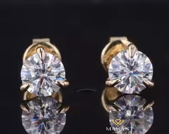 Puede incluir: Un par de pendientes de oro con una piedra preciosa redonda y transparente en el centro de cada pendiente.