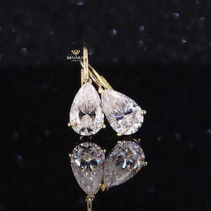 May include: A pair of gold pear-shaped dangle earrings with clear cubic zirconia stones.
