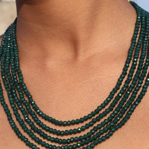 Peut inclure: Un collier multi-rangs composé de perles facettées vert foncé. Le collier est superposé et a un effet en cascade.