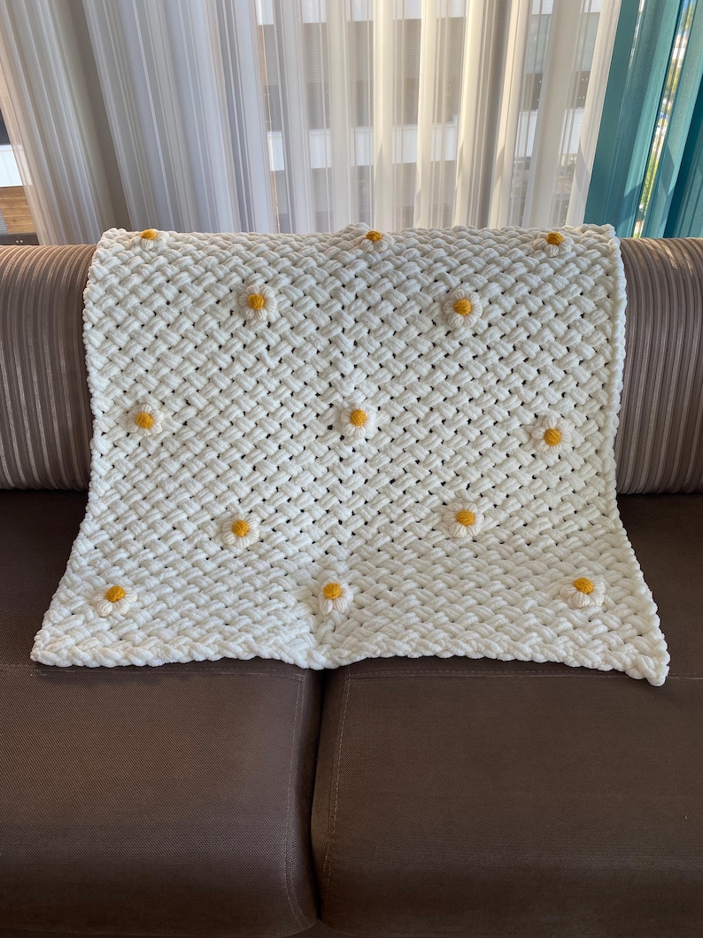 May include: White crocheted throw blanket with yellow daisy flower accents.