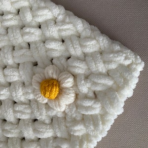 May include: White crocheted blanket with a yellow and white daisy flower accent.