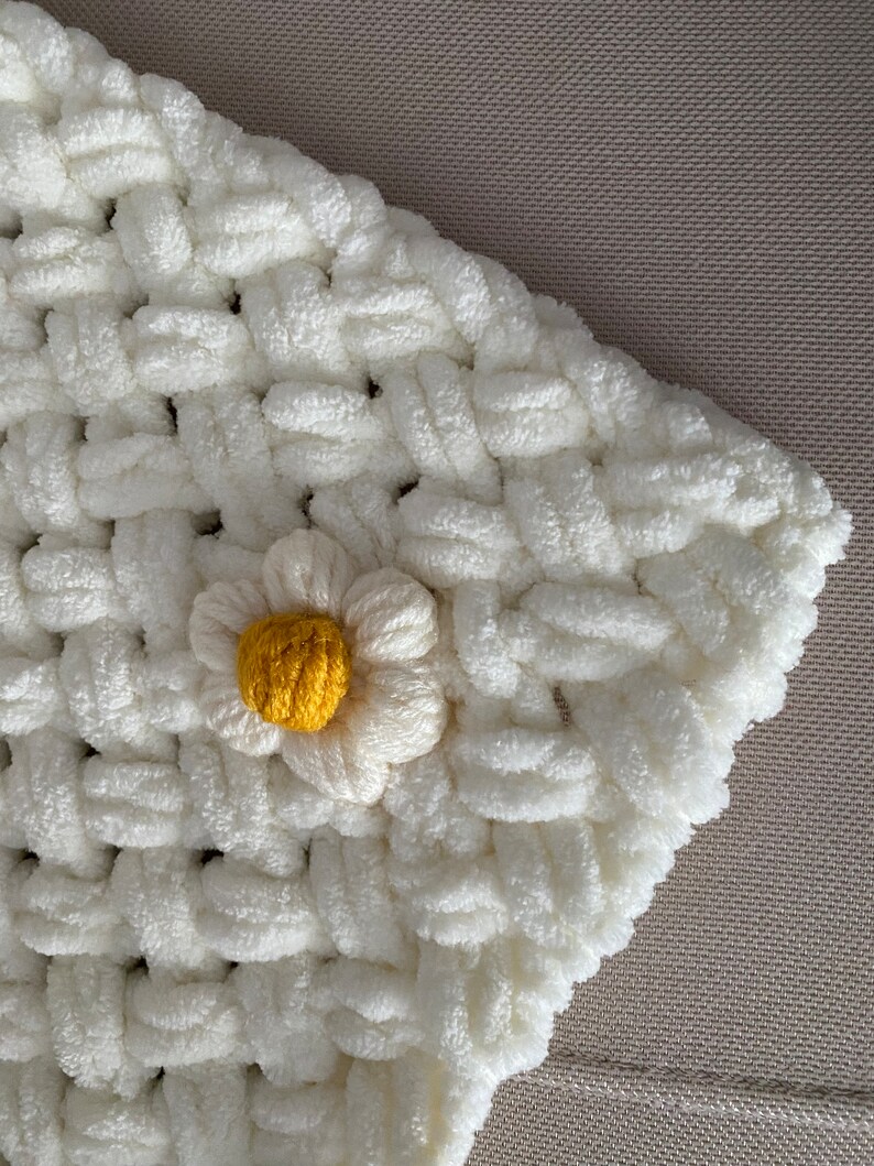 May include: White crocheted blanket with a yellow and white daisy flower accent.