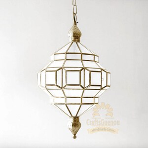 May include: A white glass Moroccan pendant light fixture with a gold metal frame. The light fixture has a geometric design and is hanging from a chain.