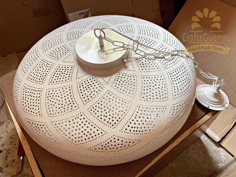 May include: White metal ceiling light fixture with a geometric pattern of holes. The light has a chain and a white metal canopy.