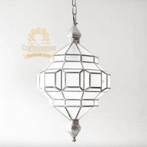 May include: A silver Moroccan pendant light with a geometric design and clear glass panels. The light is hanging from a chain.