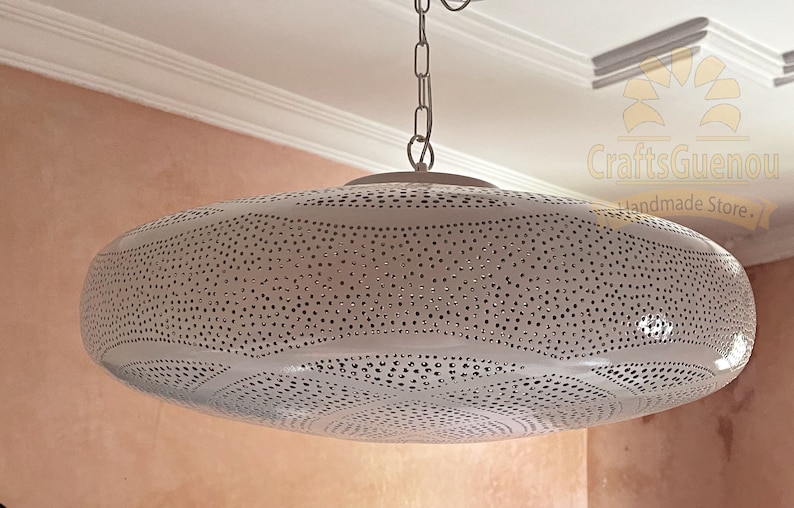 May include: White metal pendant light fixture with a round, perforated shade. The shade has a pattern of small, evenly spaced holes.