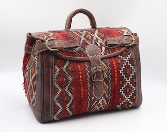 May include: A brown leather travel bag with a red, orange, and white patterned fabric. The bag has two buckles and a top handle.