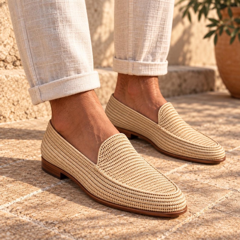 Handmade men's wedding shoes made from natural woven raffia, styled as penny loafers with a woven cross-strap detail in gray and beige tones. Unique groom footwear featuring handcrafted raffia weaving and a tan leather sole. Perfect for rustic, boho, or destination weddings. Artisan-made natural fiber loafers offering a stylish, comfortable alternative to traditional leather wedding shoes for grooms and groomsmen.