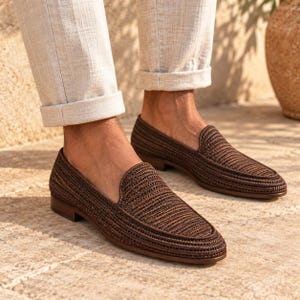 Handmade men's wedding shoes made from natural woven raffia, styled as penny loafers with a woven cross-strap detail in gray and beige tones. Unique groom footwear featuring handcrafted raffia weaving and a tan leather sole. Perfect for rustic, boho, or destination weddings. Artisan-made natural fiber loafers offering a stylish, comfortable alternative to traditional leather wedding shoes for grooms and groomsmen.