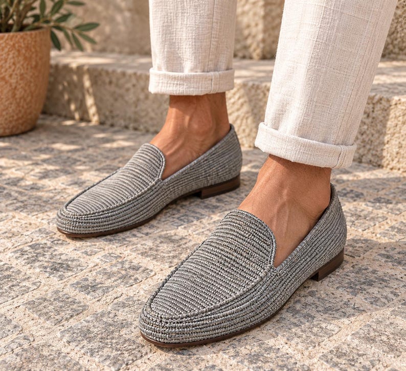 Handmade men's wedding shoes made from natural woven raffia, styled as penny loafers with a woven cross-strap detail in gray and beige tones. Unique groom footwear featuring handcrafted raffia weaving and a tan leather sole. Perfect for rustic, boho, or destination weddings. Artisan-made natural fiber loafers offering a stylish, comfortable alternative to traditional leather wedding shoes for grooms and groomsmen.