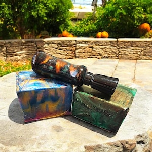 May include: A black and brown bottle stopper with a black cap, resting on two colorful blocks. The blocks are blue, green, gold, and purple.