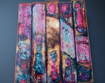 May include: Five rectangular resin pen blanks arranged side-by-side, featuring a marbled blend of metallic pink, teal, and gold pigments. Each piece displays a unique, swirling pattern with textured, iridescent surfaces and deep color saturation.
