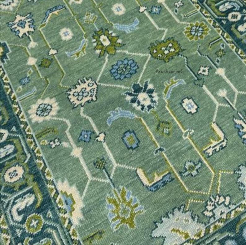 May include: A green rug with a geometric pattern in shades of blue, white, and green. The rug has a border with a more intricate design.