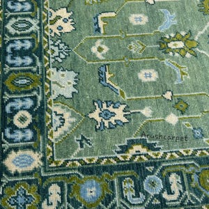 May include: Close-up of a green and blue patterned rug with a white border. The rug has a traditional design with intricate details. The text "Arushcarpet" is visible in the bottom right corner.