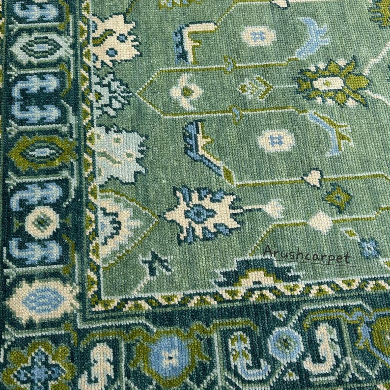 May include: Close-up of a green and blue patterned rug with a white border. The rug has a traditional design with intricate details. The text "Arushcarpet" is visible in the bottom right corner.