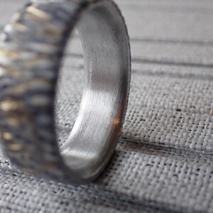 May include: A silver ring with a textured band and a smooth, polished inner surface.